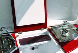 Au dos du leaning-post, la petite cuisine de plein air comporte un évier, un petit frigo et un réchaud à gaz.
