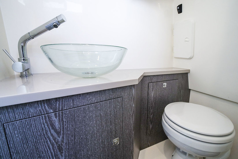 Détail du cabinet de toilette équipé d’un WC marin électrique, d’un lavabo, et d’un mitigeur qui, grâce à son flexible intégré, peut servir de douche. 