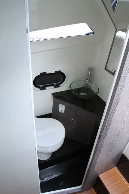Le cabinet de toilette réunit WC marin, lavabo et douche. Le hublot ouvrant permet de ventiler, le hublot fixe apporte la lumière naturelle.