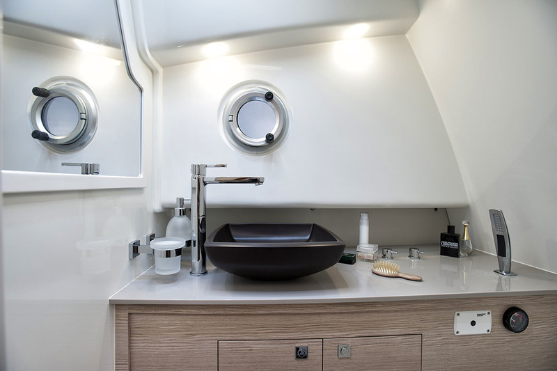 La salle d’eau joue d’une élégance sobre, avec un contraste bois clair/lavabo noir. Ce confort fait du Strider 11 un semi-rigide apte à la croisière.