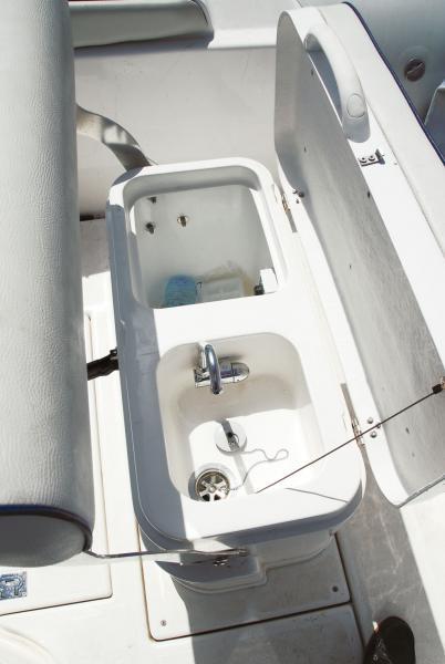 Sous la banquette de pilotage, une glacière et un évier avec eau douce suffisent pour les pique-niques, avec réchaud optionnel pour la croisière-raid.